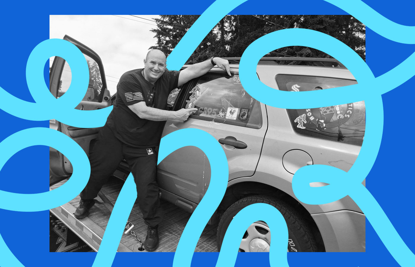 A man pointing at stickers on a car that is up on a lift.
